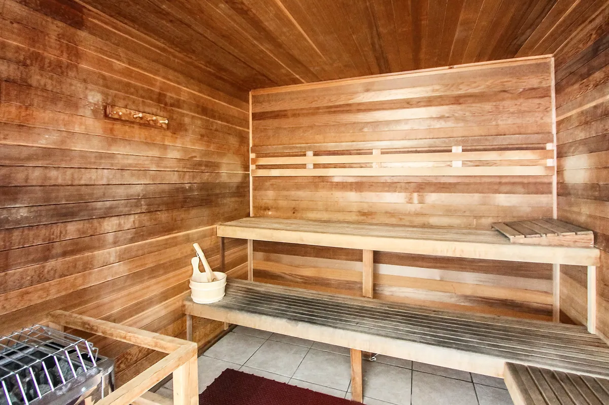 A calm and inviting sauna space with wooden benches, a sauna heater, and the classic bucket and ladle. The minimalist, warm environment is perfect for unwinding and self-care after a day of adventure.