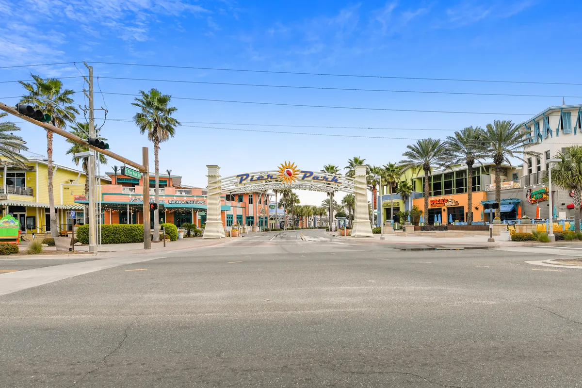A lively exterior scene featuring the Pavilion entrance, colorful buildings, and palm trees. The setting is bustling with people shopping, dining, and strolling, offering a sense of the vibrant local attractions easily accessible from the resort.