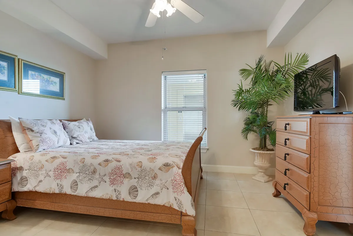 A second bedroom with a bed, dresser, potted plant, and window. The space feels cozy and tranquil, ideal for guests or children to unwind. The natural light contributes to the inviting atmosphere and sense of privacy.