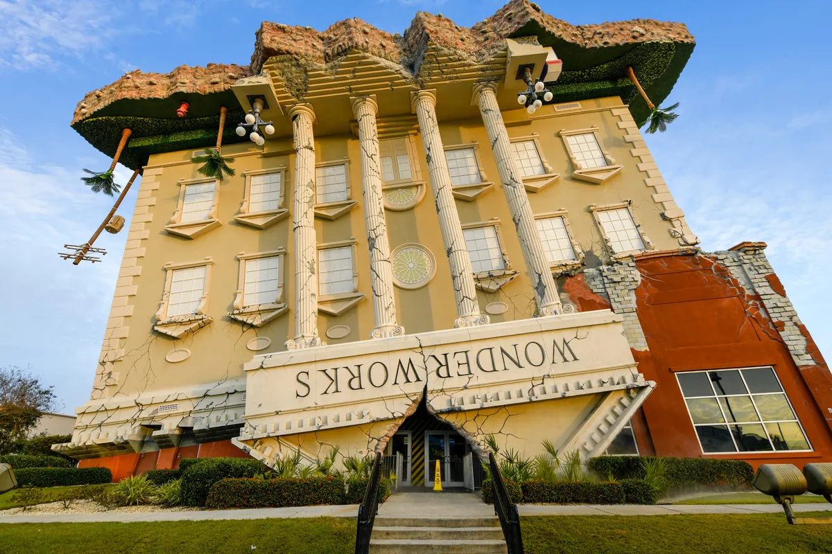 A striking image of WonderWorks, featuring its famous upside-down building design with quirky pillars and eye-catching decorative elements. The unconventional architecture draws the eye and hints at the unique, interactive experiences inside.